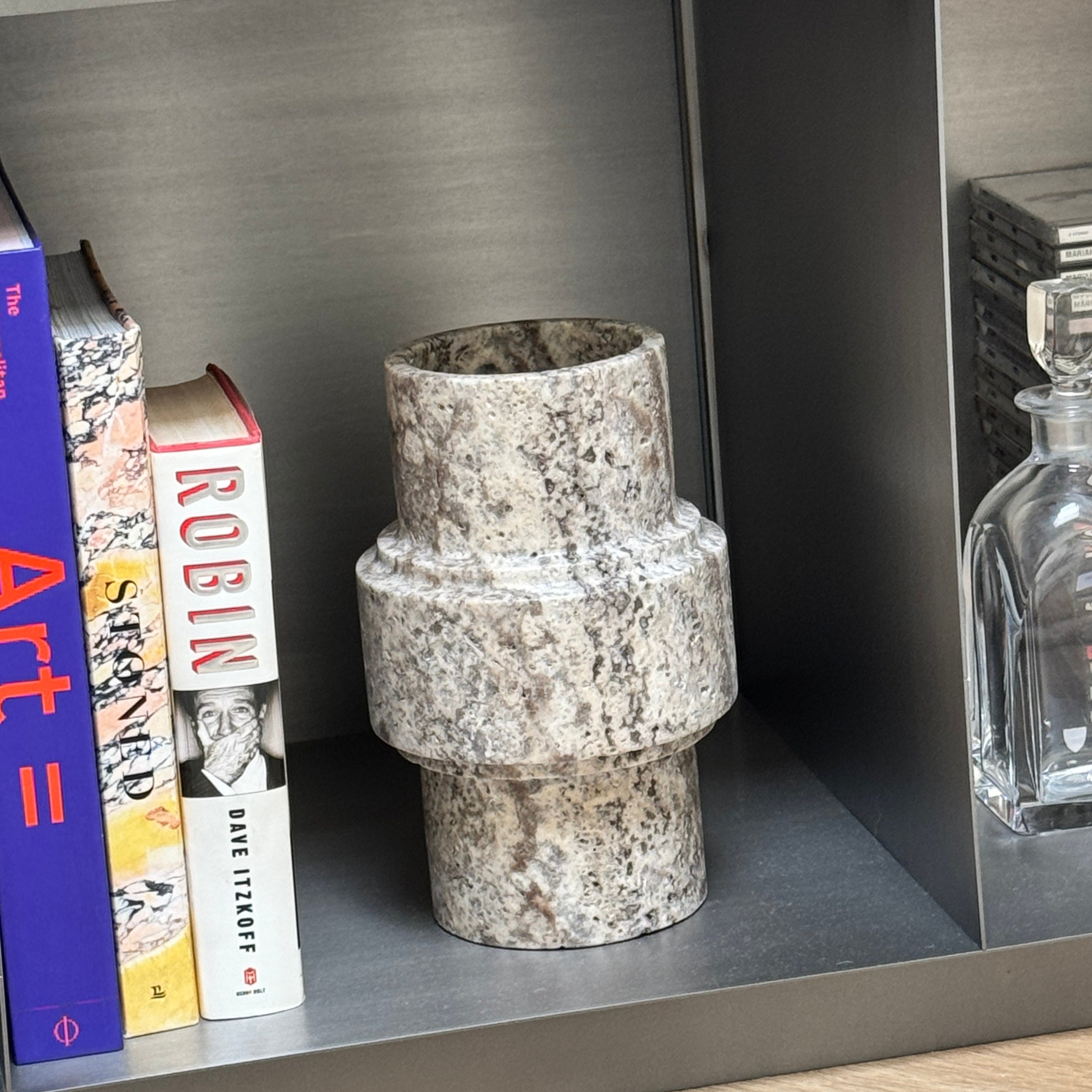 Decorative vase on a shelf with books and a decanter